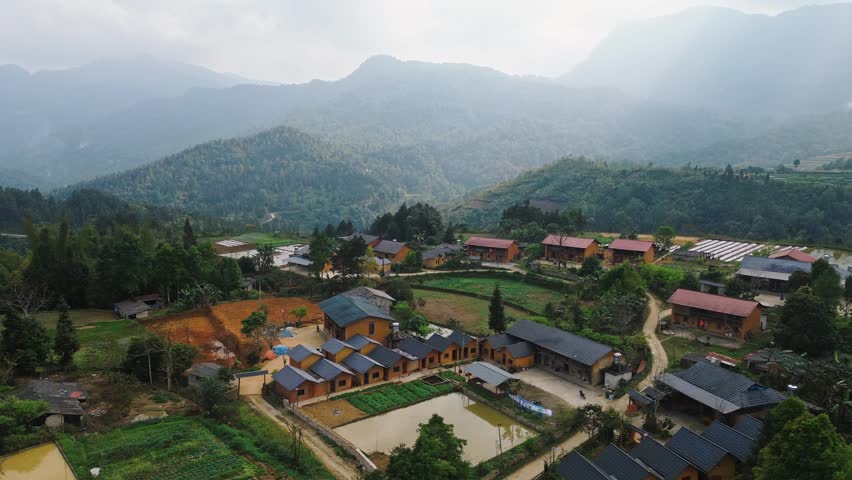 Aerial view of a peaceful ethnic minority village with colorful roofs surrounded by karst limestone peaks in Ha Giang, Vietnam