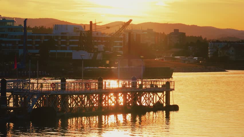 Symmetrical floating pedestrian dock at sunset in urban harbor