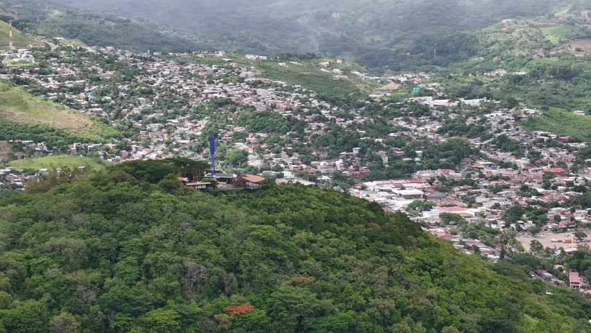 High point looking down on houses and trees in the mountains. It is a cloudy day.