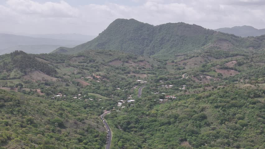 Mountain area with trees and roads. Clouds are in the sky above the land.