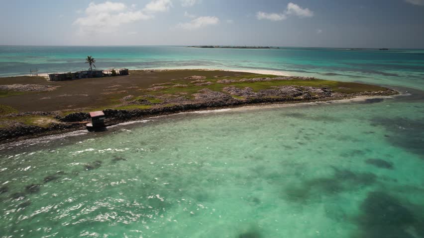 Unique marine heritage with Extensive Queen Conch shell mounds, a rustic fisherman’s shack along the shoreline, shallow crystal-clear turquoise waters, and a pristine Caribbean coastal landscape.