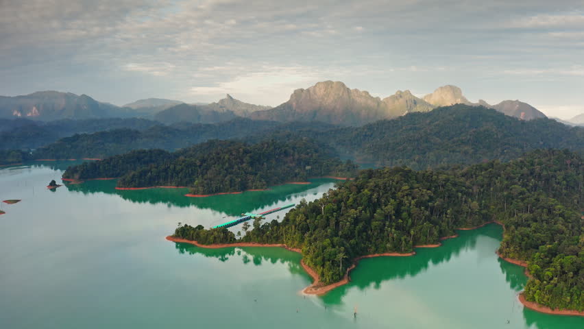 Amazing aerial landscape of Cheow Lan Lake overwater bungalow resort with turquoise waters and lush rainforest islands, surrounded by stunning limestone karsts of Khao Sok National Park in Thailand