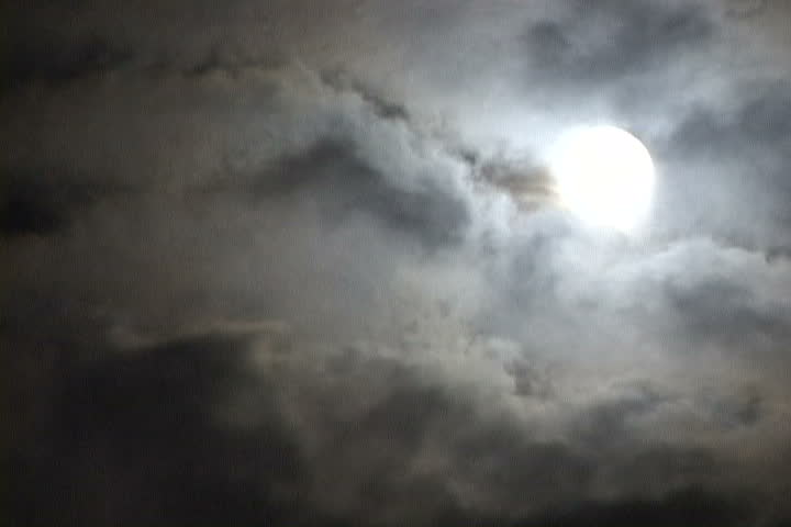 Time Lapse of Glowing, Full Moon at night as clouds move pass rapidly.