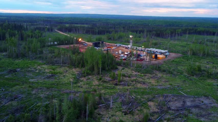 Aerial view of a drilling rig site and camp shacks at dusk in Alberta