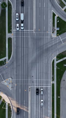 Road intersection in Winnipeg, Manitoba. Vertical drone looks straight down while descending over vehicles, sidewalks, asphalt streets, and traffic lights on a clear summer day.