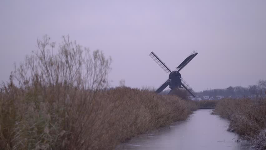 Iconic Dutch Windmills of Kinderdijk in a Frosty Frozen Winter Landscape.