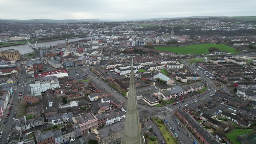 An aerial view of a dense urban landscape with a church spire at center, surrounded by roads and houses