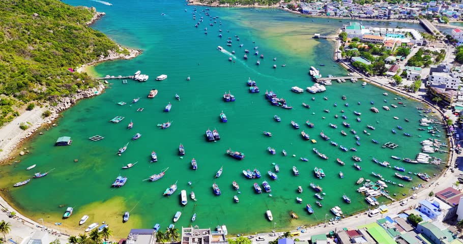 Breathtaking aerial view of Vinh Hy Bay, Vietnam, featuring emerald waters, colorful fishing boats, coastal villages, and rugged mountains. The pristine bay and vibrant marine landscape highlight the natural beauty and tropical charm of one of Vietnam’s most scenic coastal destinations.