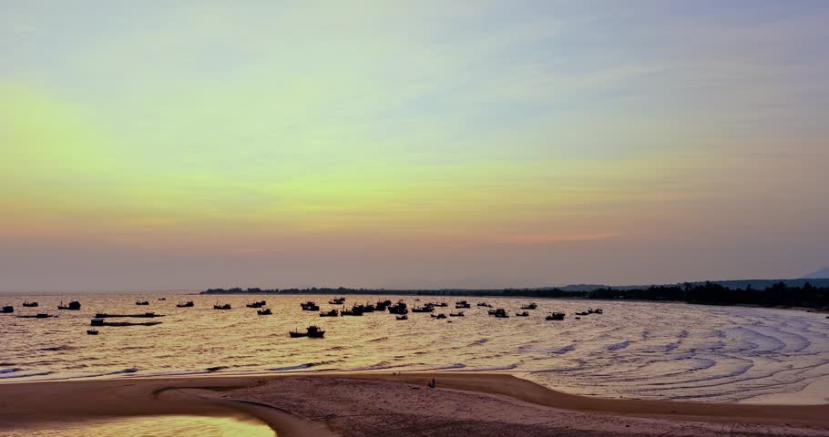 Golden sunset over Ke Ga Bay, Vietnam, featuring beautiful sandbars, gentle ocean waves, and fishing boats scattered across the horizon. The warm evening light reflects on the sea, creating a tranquil coastal landscape that showcases the natural beauty of Vietnam’s southern shoreline.