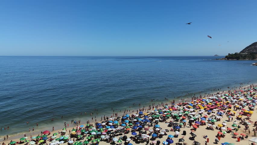 Aerial view of a crowded beach with colorful umbrellas and people enjoying the sunny day in Rio de Janeiro, Rio de Janeiro, Brazil.
