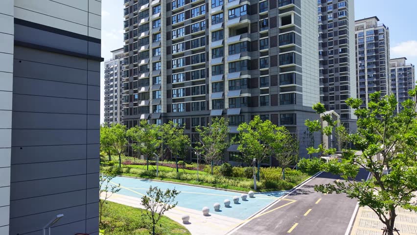 Aerial shot of dense modern high-rise residential quarter with central green garden	