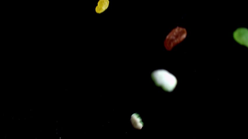 Multi-colored gummy candies and sweets freeze in mid-air against a black background.