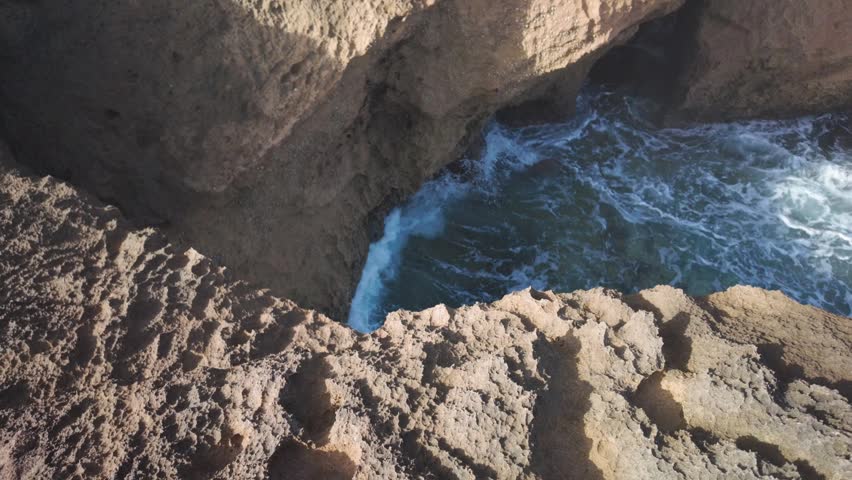 Ocean Waves Crashing in a Rocky Coastal Cave on a Sunny Day