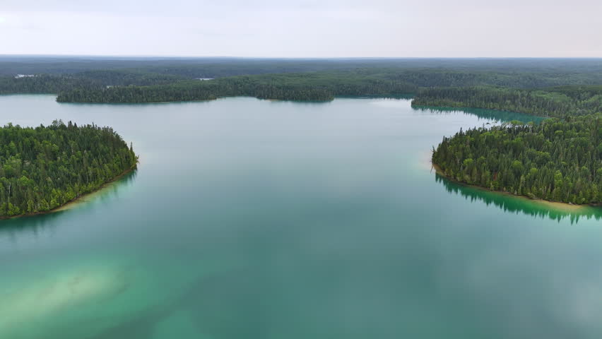 Aerial view of the striking turquoise waters of Big Skunk Lake in northern Ontario, surrounded by pristine boreal forest and peaceful wilderness.