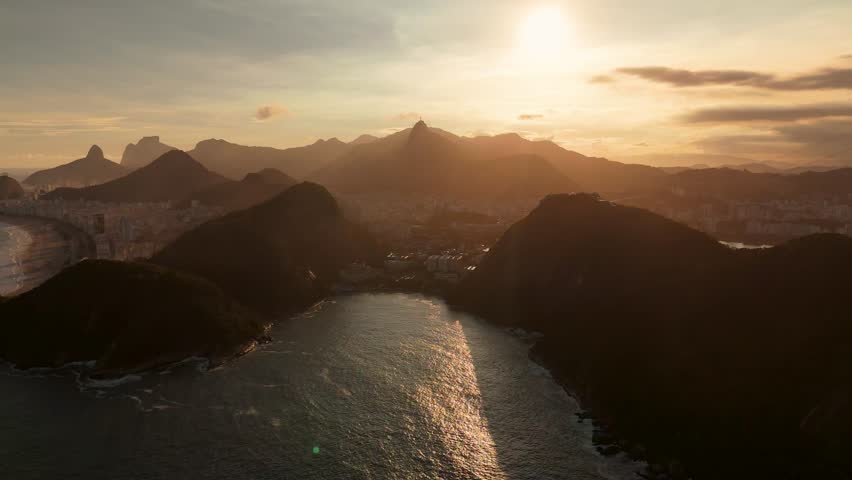 Aerial view of Christ the Redeemer statue atop Corcovado mountain overlooking the coastline and urban landscape at sunset in Rio de Janeiro, Rio de Janeiro, Brazil.