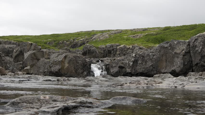 Small Waterfall Cascading Over Rocky Terrain in Iceland 4K Nature Footage