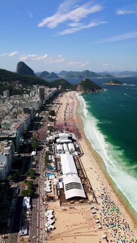 Aerial view of Copacabana Beach with a large event setup, urban buildings, and mountains under a clear blue sky in Rio de Janeiro, State of Rio de Janeiro, Brazil.