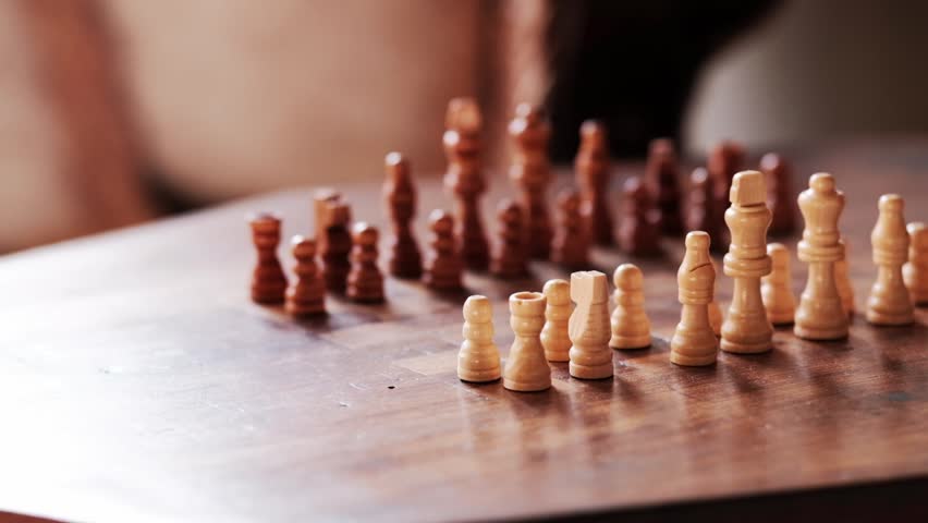 A wooden chess board setup with the white pieces in focus