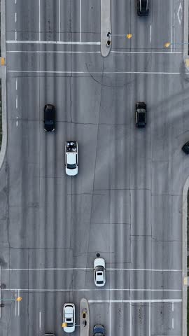 Vertical drone overhead static view of a Winnipeg intersection, Manitoba, Canada. Close view of road traffic showing cars, lanes, sidewalks, grass, streetlights, and nearby buildings.
