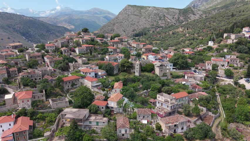 Aerial view of a winding road and dry riverbed through a mountain valley in Qeparo, Vlore County, Albania.