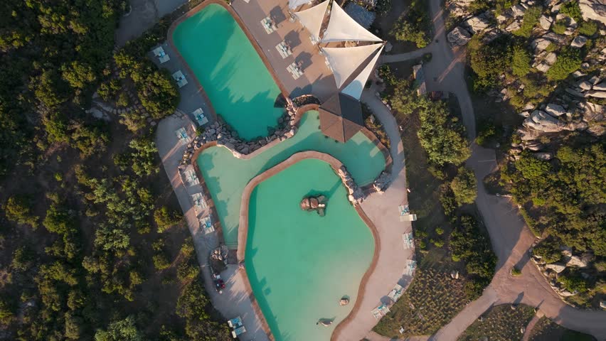 Aerial view of luxury resort pool surrounded by greenery and rocky landscape