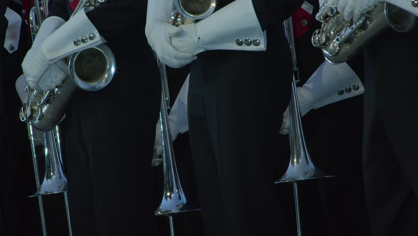 Pan across marching band in uniform holding silver brass instruments