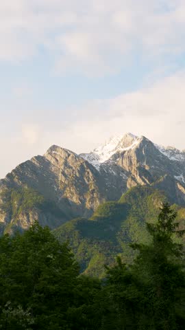 Sunset light illuminating snowy Julian Alps above Bovec valley, vertical pan right