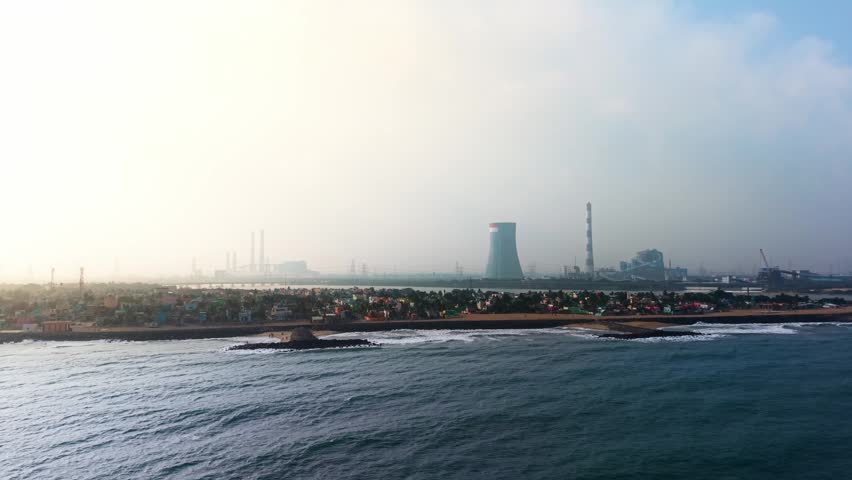 Coal fired thermal power plant with cooling towers on the sea shore emitting smoke