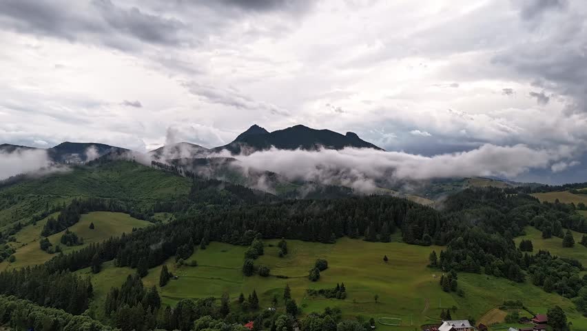 Aerial Hyperlapse Mountain Village With Dramatic Clouds and Fog Over Rocky Peaks