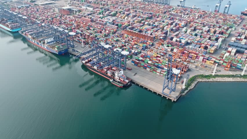 4K aerial view of massive container ship and gantry cranes at Shenzhen Port, global maritime trade hub in China.