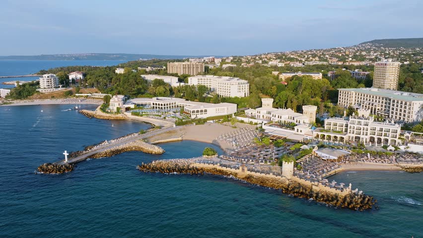 Beautiful coastline of Saints Constantine and Helena resort with stone breakwaters sandy bays and hotels on green hills background aerial drone panoramic shot.