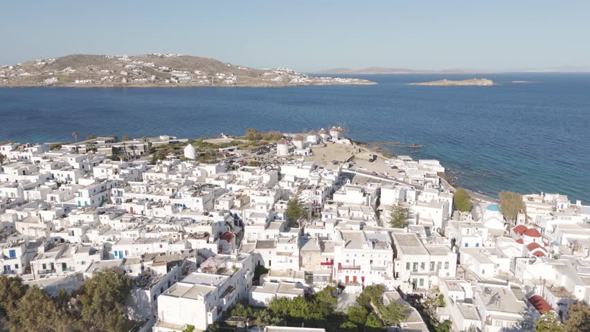 Panoramic aerial view of Mykonos town with the famous windmills and white houses by the Aegean Sea