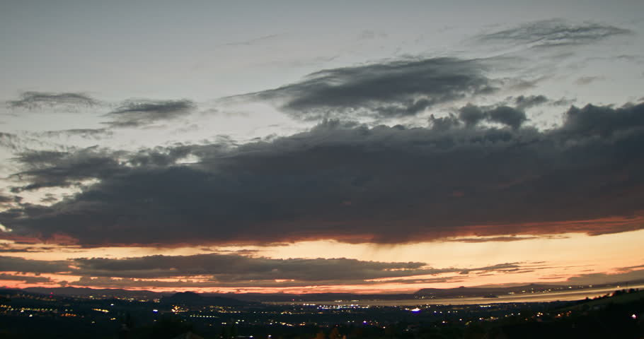 Dramatic sunset over the Pentland Hills with Edinburgh city lights beneath layered clouds. Warm evening glow creates a peaceful atmospheric Scottish landscape.