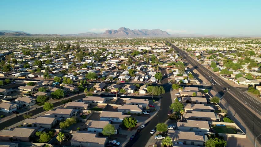An Aerial view of a suburban neighborhood in Phoenix, Arizona, with grid-like streets and distant desert mountains