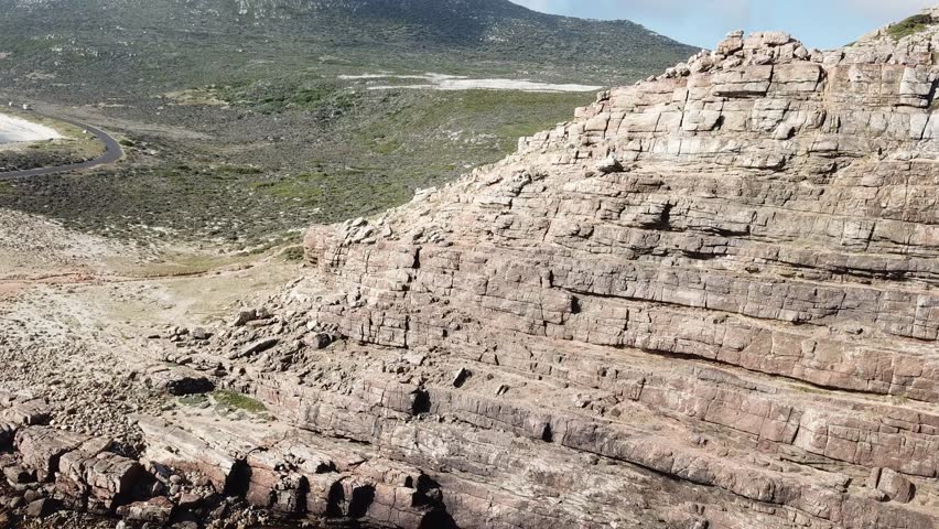 Stunning aerial drone footage of the Cape of Good Hope in South Africa, showcasing dramatic rocky cliffs, the vast blue Atlantic Ocean, and a rugged coastline.