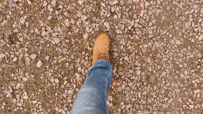 View of legs in brown boots during a walk in the park in autumn