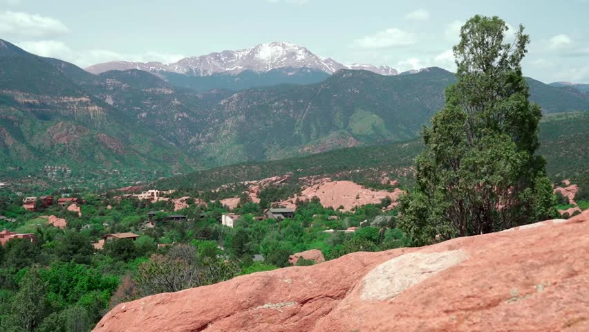 An aerial shot panning from rugged red rock spires to dense green forest in Garden of the Gods, Colorado