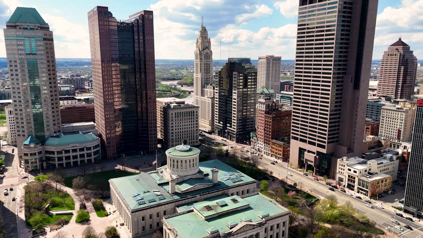 A cinematic drone shot capturing the modern skyline of Columbus, Ohio, USA, showcasing downtown architecture, urban development, office buildings, streets, and the vibrant atmosphere of the state capital on a clear day