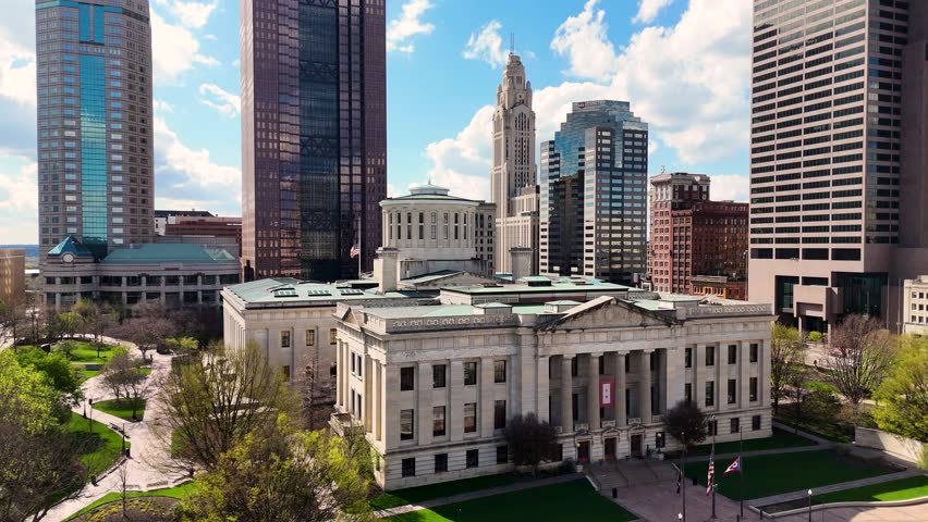 A cinematic drone shot capturing the modern skyline of Columbus, Ohio, USA, showcasing downtown architecture, urban development, office buildings, streets, and the vibrant atmosphere of the state capital on a clear day
