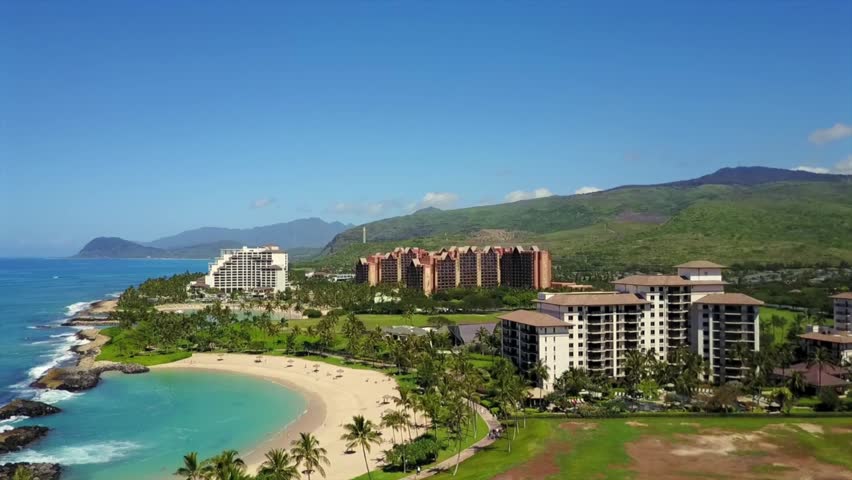 A resort community with marina, curving beach lagoons, and vibrant tropical foliage under a bright sky in Ko Olina, Hawaii