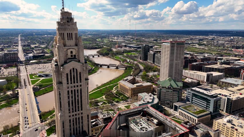A cinematic drone shot capturing the modern skyline of Columbus, Ohio, USA, showcasing downtown architecture, urban development, office buildings, streets, and the vibrant atmosphere of the state capital on a clear day