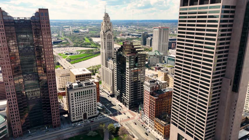 A cinematic drone shot capturing the modern skyline of Columbus, Ohio, USA, showcasing downtown architecture, urban development, office buildings, streets, and the vibrant atmosphere of the state capital on a clear day