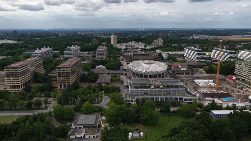 An expansive aerial view of the Ruhr University campus in Germany, showcasing its unique modernist architecture amidst lush green trees