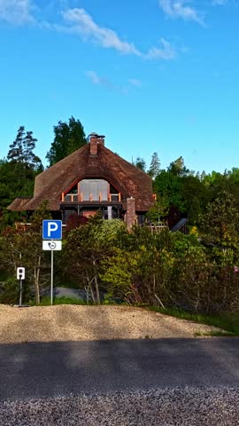 Aerial view of a traditional house with a thatched roof nestled in the lush green landscape of Amatciems, Cesu novads, Latvia.