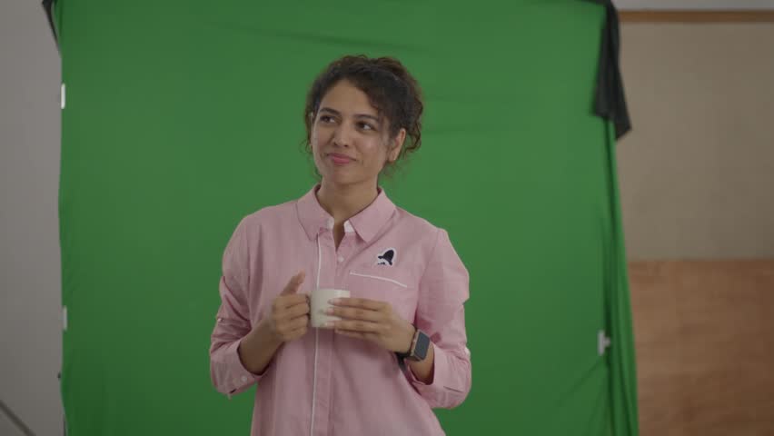 An Asian model glancing sideways with a soft smile while holding a cup during a relaxed studio shoot