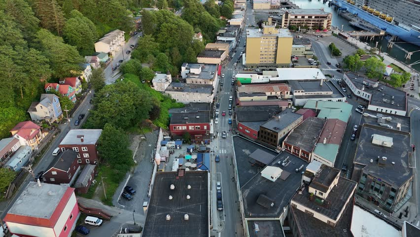 An aerial footage of the cityscape of Juneau, Alaska, USA shows busy streets, mixed architecture, dense trees, and harbor infrastructure