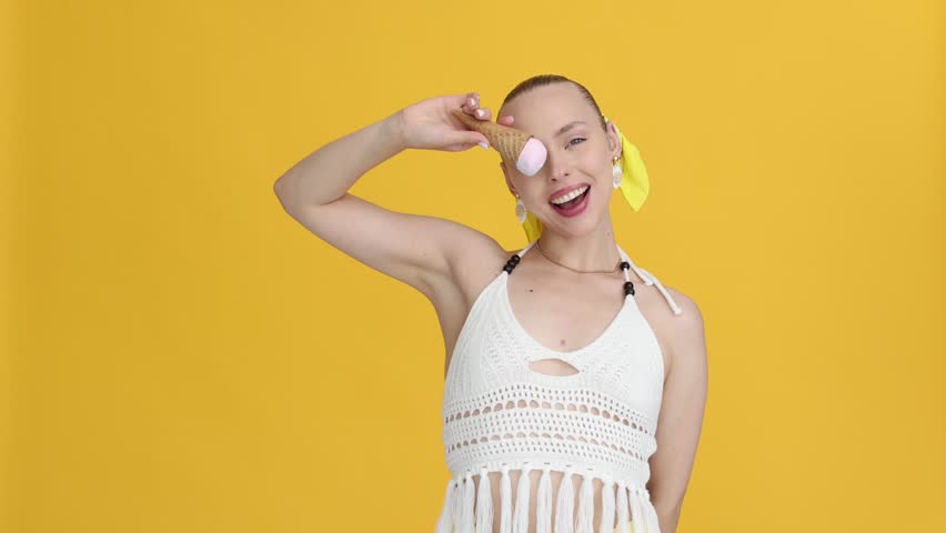 Woman with delicious ice cream in waffle cone on orange background