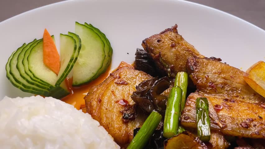 Crispy chicken stir fry with jasmine rice, charred golden pieces and green vegetables with cucumber slices, savory garlic soy