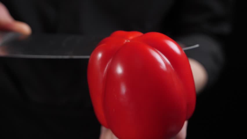 Chef cutting fresh red bell pepper with sharp knife