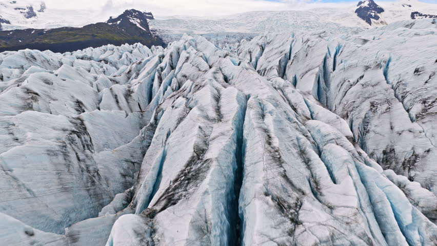 Cinematic aerial flight above the spectacular glacier front of Fjallsárlón Glacier Lagoon in Iceland, revealing deep crevasses, blue glacial ice and the dramatic landscape of Vatnajökull.